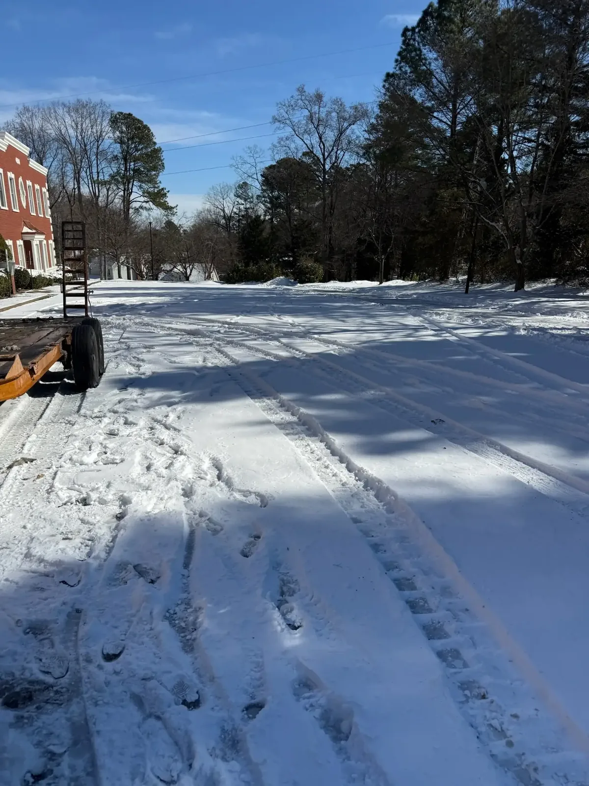 Home 19 Fonvilletreeservice snow-covered commercial parking lot with tire tracks and footprints after winter storm in NC